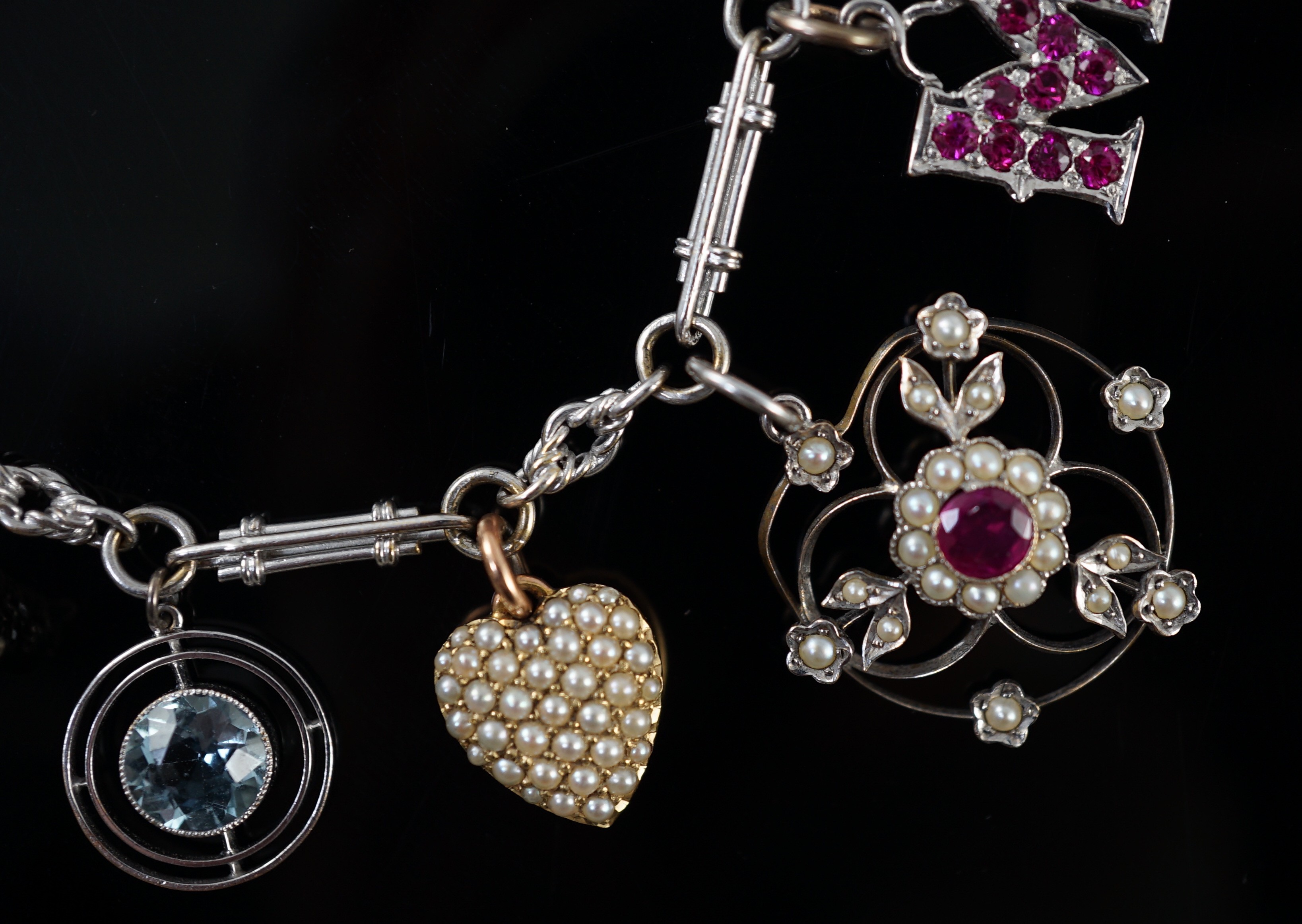 A French 18ct white gold circular and baton link charm bracelet, hung with eleven assorted charms